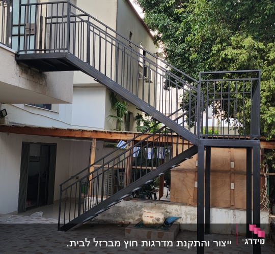 גרם מדרגות מתכת עם מעקה שחור בחצר